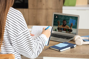 Teenage girl studying Math with tutor online in kitchen, closeup