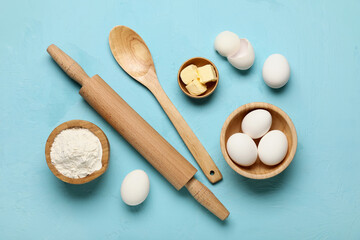 Composition with fresh chicken eggs, butter, flour and wooden kitchen supplies on color background