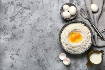 Composition with bowl of flour, fresh chicken eggs and whisk on grunge background