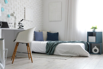 Interior of light teenager's room with bed and workplace