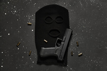 Balaclava with gun and bullets on dark background