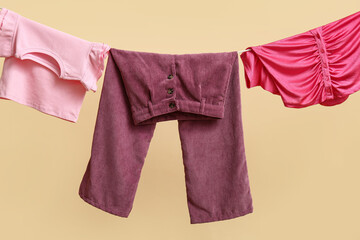 Clean clothes hanging on clothesline against color wall