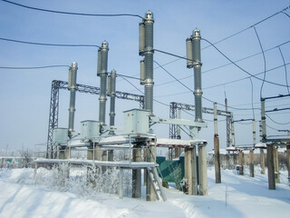 Electrical substation with high voltage equipment in winter season. Power plant infrastructure...
