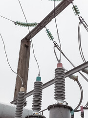 Electrical substation detail on a cloudy day. High voltage power supply equipment and insulators with concrete pillar. Power generation industry.