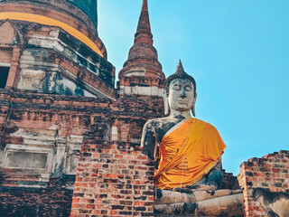 Close-up view of large Buddha statue draped in yellow robes in Ayutthaya, Thailand. 