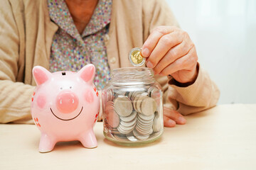 Retired elderly woman counting coins money with piggy bank and worry about monthly expenses and...