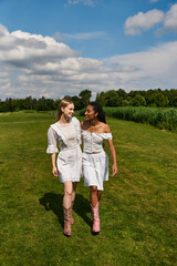 Young couple joyfully walking hand in hand across a sunlit meadow on a beautiful summer day