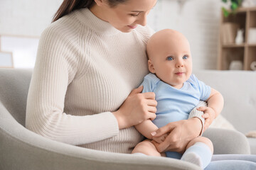 Mother with her little baby sitting on couch at home, closeup