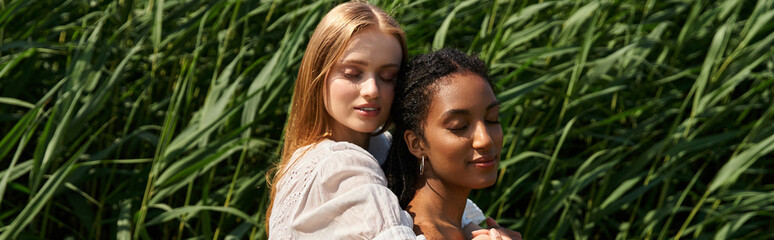 Naklejka premium Beautiful young couple sharing a tender moment in a lush green field under the sun
