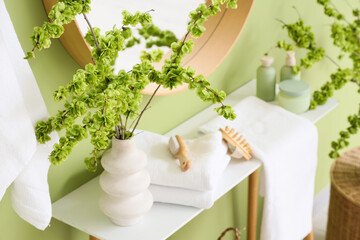 Vase with blossoming branches on table in bathroom, closeup