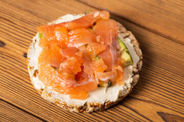 Toast cereal with red fish, cheese and avocado. Healthy breakfast. Wood background, cottage cheese