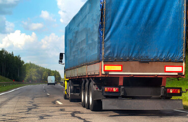 Transportation of consolidated cargo for online stores by trucks with semi-trailers along the highway in the summer. Insurance of cargo and vehicles of transport companies. Copy space for text