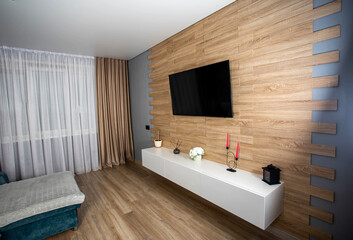 Modern interior in the living room with wooden laminate flooring, wall-hung cabinets, LCD TV and air conditioning. Stylish renovation in the apartment. Copy space for text