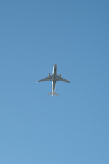 Airplane in the sky from below. Airplane suitable as an isolated object for animation. Airliner in flight photographed from the ground, looking up into the sky. Bottom of an airplane. Blue sky.