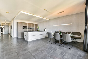 A sleek and contemporary kitchen space featuring a minimalist design with dark cabinetry and an elegant dining table setup perfect for gatherings.