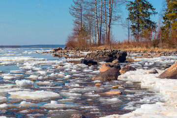 Spring landscape, warm April day by the lake, melting ice on the water.