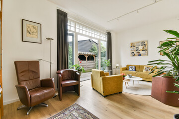 A modern living room featuring stylish furniture and large windows that let in ample natural light, creating a warm and inviting atmosphere.