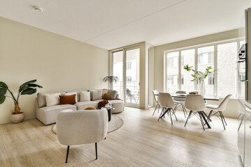 A spacious, modern living room featuring minimalist furniture, large windows for natural light, and indoor plants enhancing the contemporary aesthetic.