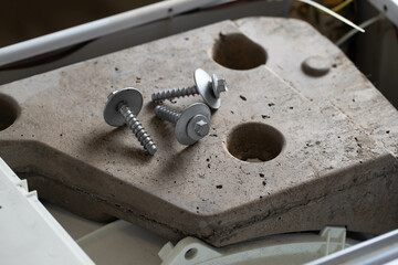 Bolts and tools lie on the counterweight of the washing machine. Concept of noise, vibration and rumble due to an unscrewed counterweight, industry