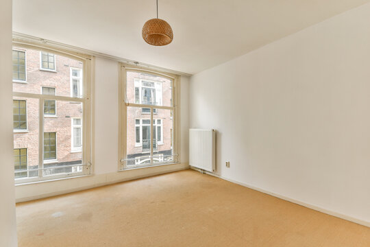 A spacious, modern room featuring large windows that allow for natural light to fill the space. The minimalist design emphasizes simplicity and elegance.