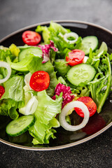 Vegetable salad tomato, cucumber, lettuce, green leaf lettuce, onion appetizer vegetable dish fresh gourmet food background rustic food top view copy space keto and paleo diet vegetarian vegan food