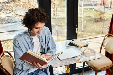Handsome young man enjoys writing in a cafe while sipping coffee during a sunny afternoon