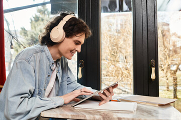 Young man enjoys leisure time at a cozy cafe while using a tablet for creative activities