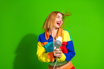 Expressive young woman with vibrant fashion style celebrating with joy on a green background,...