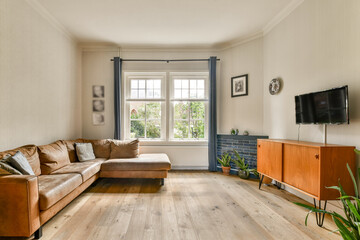 A bright and inviting modern living room featuring a comfortable couch, wooden flooring, large windows, and stylish decor accentuating the serene atmosphere.