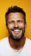 Fototapeta premium Man with graying beard, smiling in white shirt before vibrant yellow background