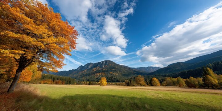 A stunning view of majestic mountains adorned with autumnal colors, under a bright blue sky with fluffy clouds, embodying the beauty and tranquility of nature in fall.