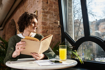 Young handsome man enjoying a leisurely afternoon reading indoors at a cozy cafe