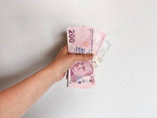 Hand holding a stack of Turkish Lira banknotes, representing finance, currency, and economic concepts