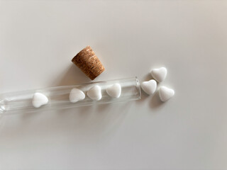 Heart-shaped pills in glass tube with cork on white background. Concepts of love, health, or science