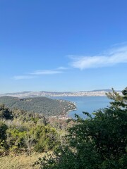 Scenic vista overlooking the sea from a lush green hill on a bright sunny day with a clear blue sky, perfect for a travel brochure