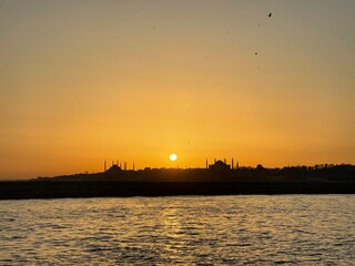 Golden sunset over istanbul mosques and minarets, city skyline silhouette reflected on golden water, tranquil travel location for tourism and vacation.
