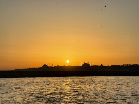 Golden sunset over istanbul mosques and minarets, city skyline silhouette reflected on golden water, tranquil travel location for tourism and vacation.
