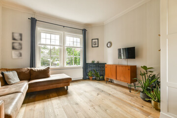 A beautifully designed living room featuring a comfortable sofa, wooden flooring, and large windows...