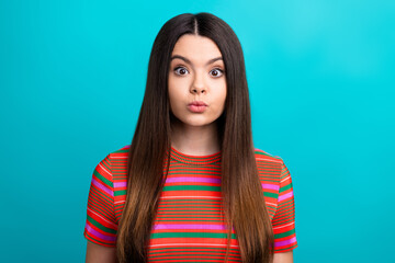 Young Woman with Playful Expression Poses Against a Vibrant Turquoise Background in Casual Striped...