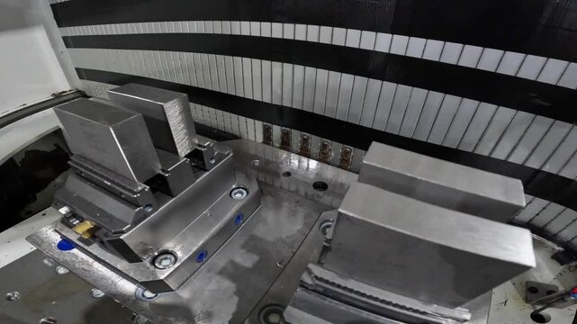 Aluminum blocks in vices inside milling booth of fabrication workshop