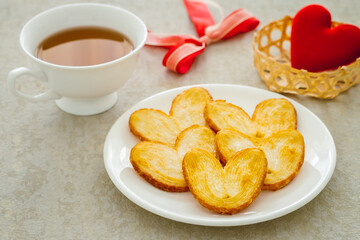 Crispy heart or butterfly puff pastry cookie and cup of tea