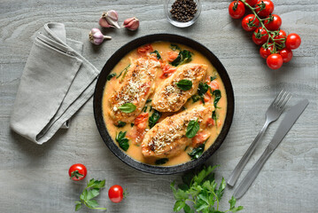Chicken breast in creamy sauce with tomatoes and spinach in pan