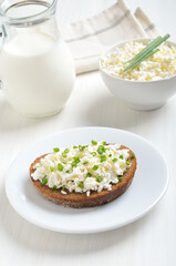 Bread with curd cheese and green onion on white plate