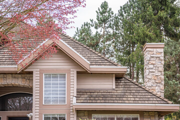 Top of grey stucco luxury house with shingle roof, trees and nice windows in Spring in Vancouver, Canada, North America. Day time on April 2025.