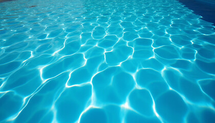 The clear blue surface of swimming pool water ripples gently under the sun, reflecting bright light and creating shimmering caustic patterns, evoking a refreshing summer feeling.