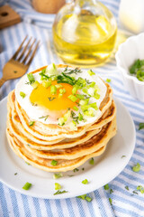 Tasty savory breakfast pancakes with spring green onion and fried eggs. Stack or delicious...