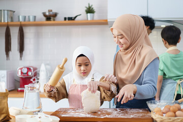 Asian muslim woman and lovely young daughter are preparing and cooking in the kitchen.