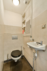 A sleek and minimalistic modern bathroom featuring a black toilet and a small sink, showcasing smart space utilization with clean lines and neutral tones.