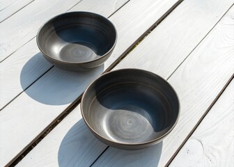 Gray bowls rest on a white wood table; an aerial perspective captures the empty stillness.
