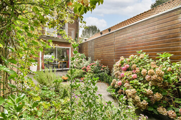 A serene garden featuring various vibrant flowering shrubs, surrounded by lush greenery and a wooden fence. Perfect for relaxing or enjoying nature's beauty.